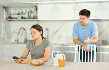 Guy argues with girl in kitchen, expressing his dissatisfaction and indignation