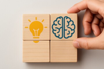 Conceptual Brainpower: A creative mind conceptualizes an innovative solution, represented by wooden blocks featuring a lightbulb and a brain, and a person's hand demonstrating concept 