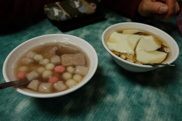 Two bowls of food, one of which is a soup with meat and noodles, Toufa