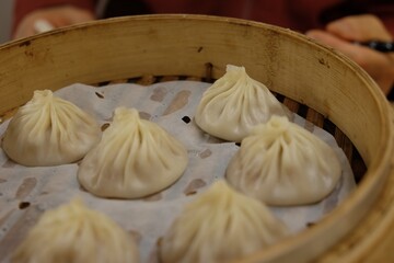 A bowl of dumplings is steaming in a bamboo steamer