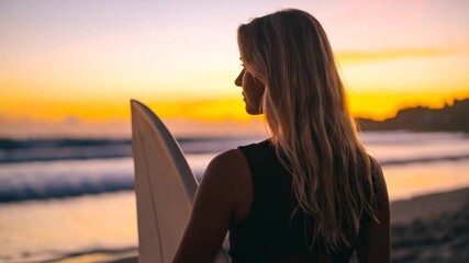 Woman holds surfboard sunset beach