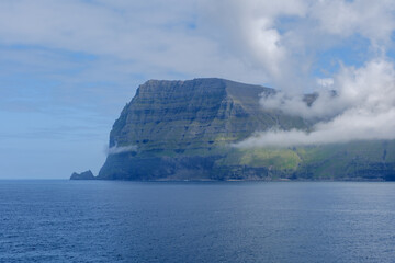 Majestic cliffs and serene waters of the Faroe Islands under a cloudy sky