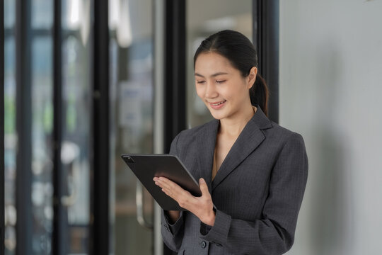 Smiling female office worker checking reports and using a digital tablet at the office.
