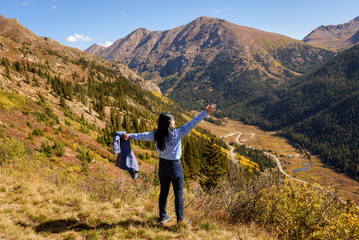 A woman enjoys a scenic autumn road trip through Colorado