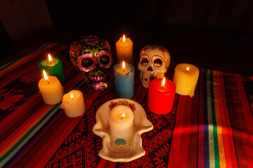White and black ceramic skulls with metallic floral details and colorful candles on traditional altar