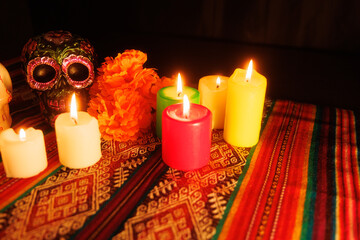 Traditional Day of the Dead altar with black skull, vibrant candles and magnolia flowers on folk cloth