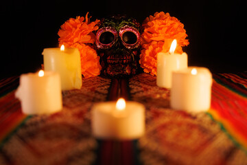 Traditional Mexican altar with black skull decorated with metal flowers and surrounded by candles and magnolias