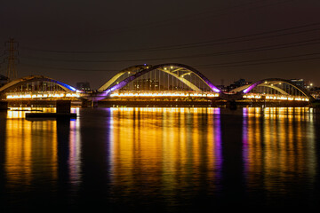 Fototapeta premium Hatirjheel Bridge at Night with City Skyline and Reflections - Dhaka, Bangladesh