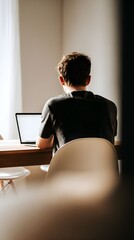 Over-the-Shoulder View of Young Man Working on Laptop – Minimalist Interior with Soft Morning Light