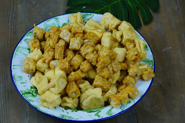 A plate of fried tofu and tempeh on a wooden table.