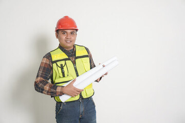 Fototapeta premium Asian construction worker wearing safety vest and helmet, holding project paper plans. Isolated image on white background