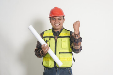 Asian construction worker wearing safety vest and helmet, holding project paper plans while pointing and giving a thumbs up, showing confidence and approval