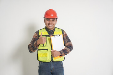 Asian construction worker wearing safety vest and helmet, raising his hand and showing a thumbs up gesture, expressing approval and confidence. Isolated image on white background