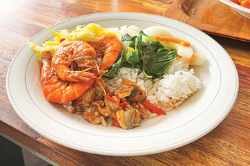 Indonesian traditional meal with rice shrimp clear soup vegetables and mango chili sambal