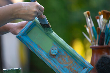 Painting a wooden furniture outdoors, an eco-friendly re-use business.