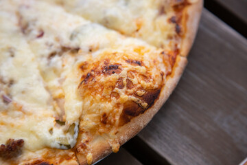 Close-Up View of a Cheesy Pizza Slice on a Wooden Table