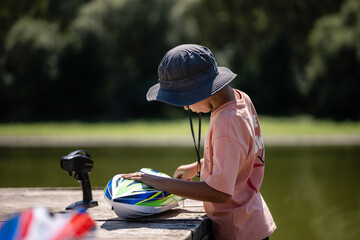 Boy preparing toy boat for racing on wooden dock