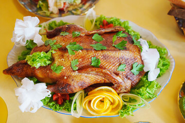 Delicious roasted duck served on a platter with fresh vegetables and herbs