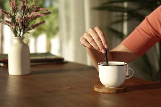 Woman hand at sunset at home stirring coffee - Powered by Adobe