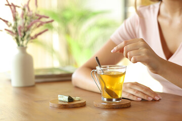 Woman hand throwing sugar cube on tea cup at home
