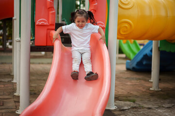 happy toddler baby girl sliding and playing at playground