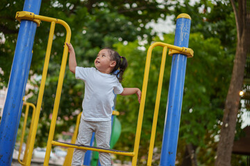 Fototapeta premium happy toddler girl playing and climbing on outdoor playground at park