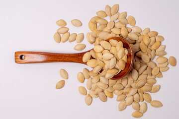 Pumpkin seeds in a wooden spoon on a white background, top view, copy space