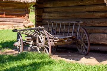 old wooden cart with large wheels standing near a wooden Ukrainian house in the yard