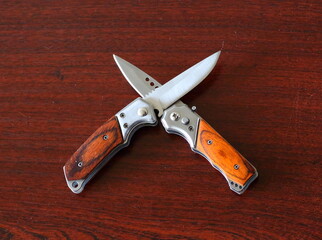 Two small knives are crossed on a wooden surface