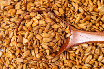 Close-up of peeled sunflower seeds in teriyaki sauce in a wooden spoon