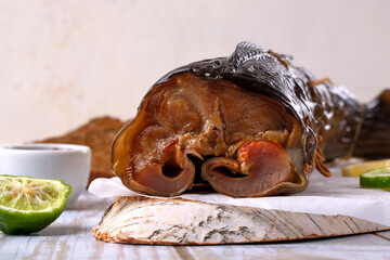 Hot smoked catfish clarias on parchment paper on white table