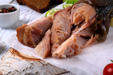 Pieces of hot smoked catfish clarias on parchment paper. Close-up