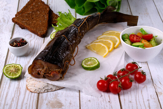 Hot smoked catfish clarias on parchment paper on white table