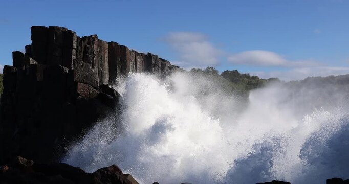 A huge whitewash wave crashes and explodes into a large basalt rock formation. Captured in slow motion during an east coast low storm swell event.