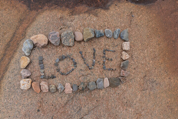Pebble letters spelling LOVE arranged on a rock at the beach of Jussaro Island. A creative and sentimental expression in a remote, scenic coastal location