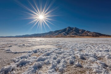 Sunburst over snowy, icy flatland and distant mountains