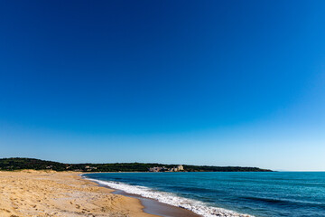 Seascape with beach, waves, sun and empty blue sky