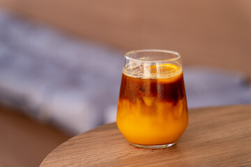 Refreshing Iced Bumble Coffee in Clear Glass on Wooden Table. Iced drink made with espresso and orange juice