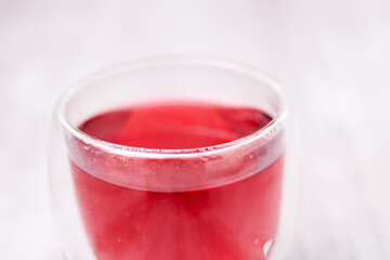This is a detailed closeup image of a glass containing red liquid