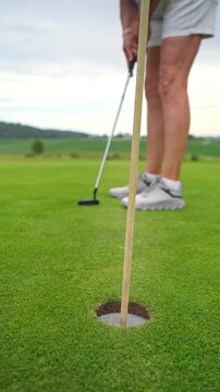 Active senior woman playing golf on a scenic course with rolling hills, enjoying outdoor exercise and vibrant retirement on a sunny summer day.