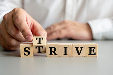 Hand arranging wooden blocks to spell the word strive
