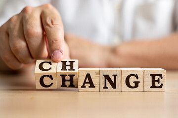Hand arranging wooden blocks to spell the word change