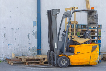 Used Yellow Electric Forklift in Front of Warehouse Building Wooden Pallets