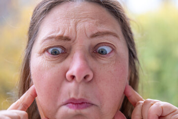 Woman covering ears with pained expression, Emotional portrait showing discomfort loud noise,...