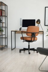 Stylish workplace with wooden desk, lamp and computer indoors