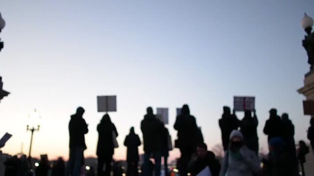 People holding signs in silhouette at a peaceful protest, a collective voice for justice.