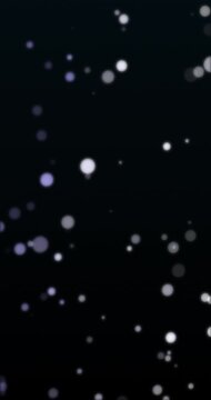 Bokeh particles floating in black background. Loop. 4K Vertical