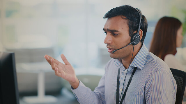 Focused male agent provides helpful tech support and excellent customer service from modern call center. He shows concern on call while assisting client with technical issue
