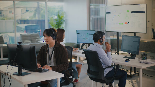 Focused tech support agent provides excellent customer service from busy call center office. helpful operator offers solutions and assistance to clients