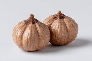 Obraz premium Two small tan gourds with ribbed surfaces rest on a white surface